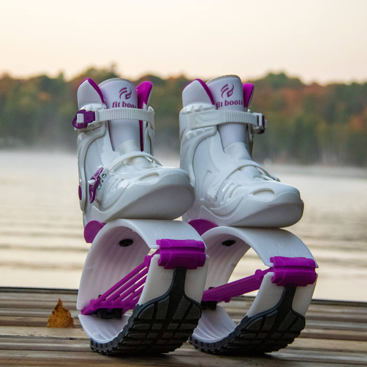 Paire de Fit Boots Rebound Boots blanches et violettes placées sur une surface en bois près d'un lac