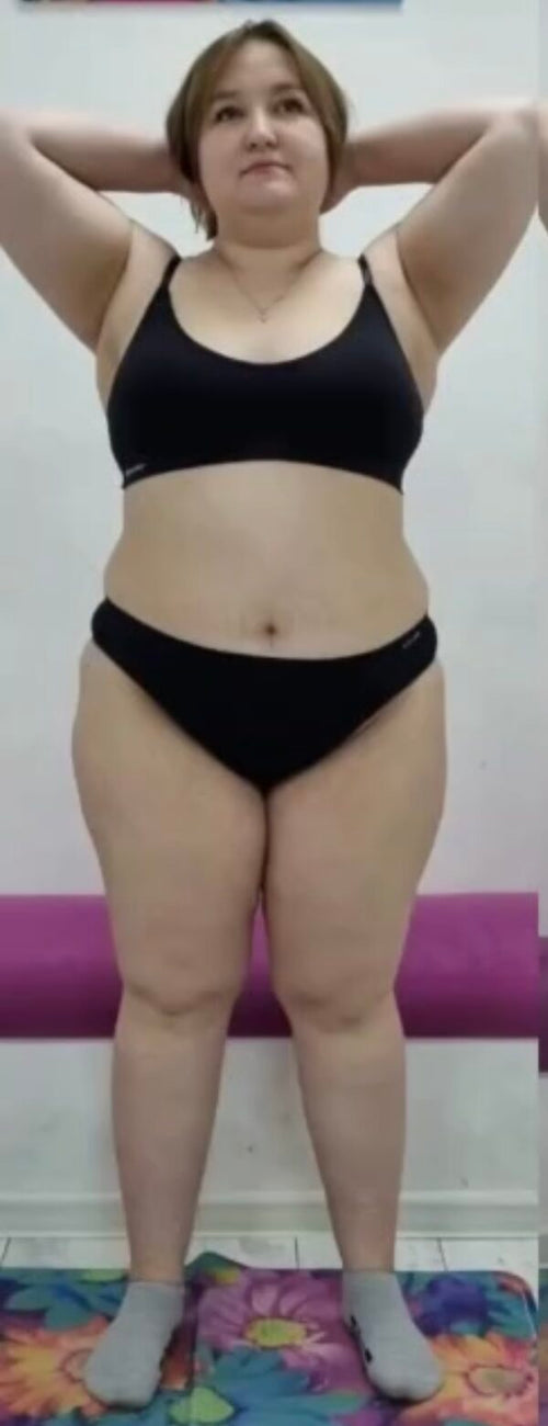 Person wearing a black sports bra and shorts on a plain background