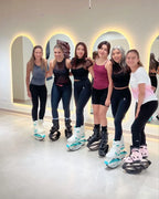 Group of six women posing together in a modern indoor setting with glowing arches.
