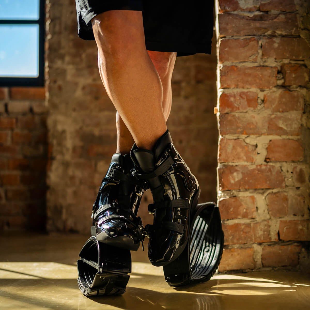 Nahaufnahme einer Person, die mit gekreuzten Beinen steht, während sie Fit Boots Rebound Boots in einem Haus trägt.