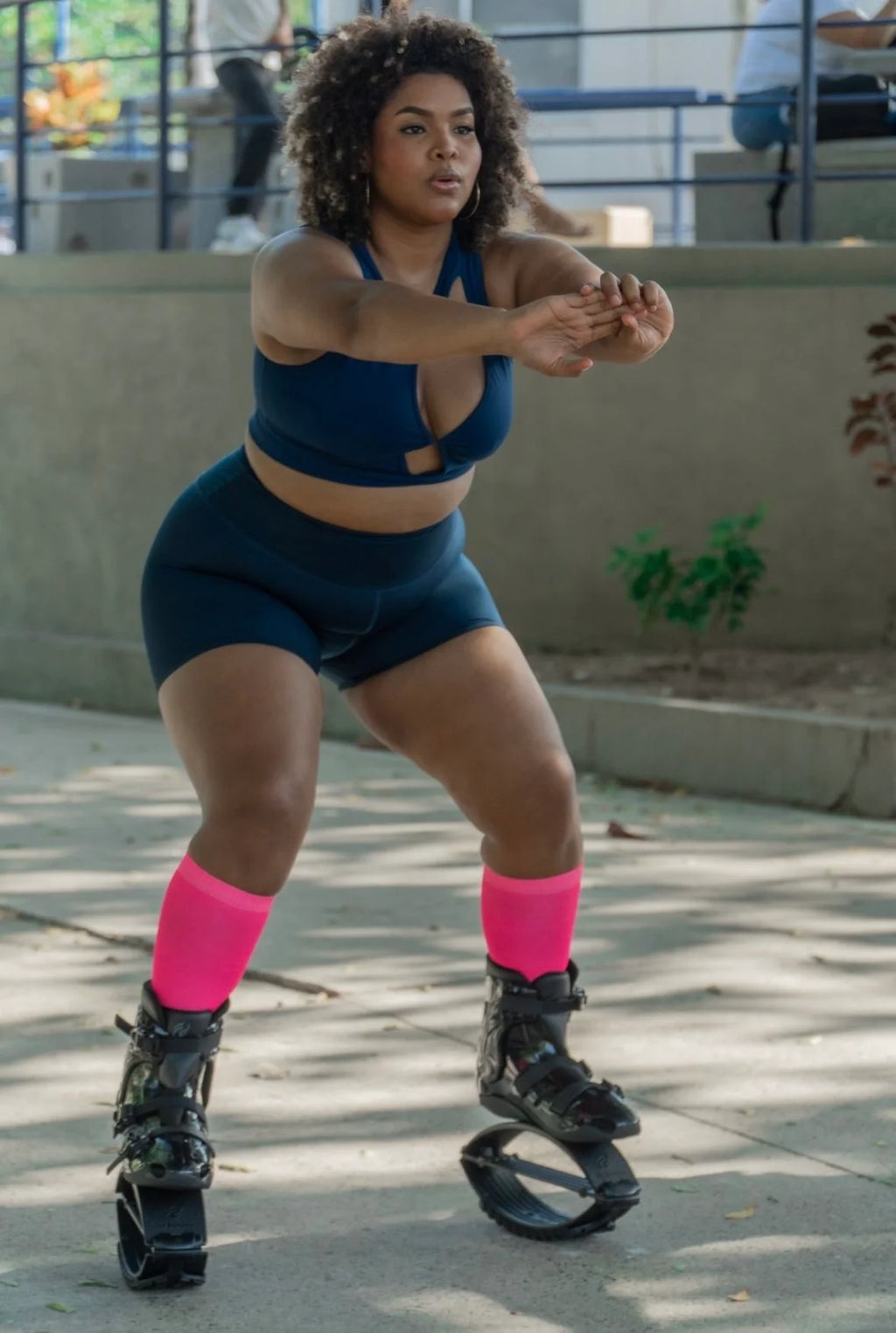 Persona vestida con un conjunto deportivo azul con calcetines rosas y zapatos negros con ruedas al aire libre.