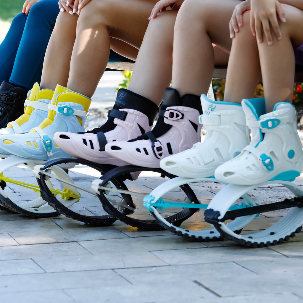 Primer plano de varias personas sentadas en un banco, mostrando sus botas de rebote Fit Boots de varios colores."